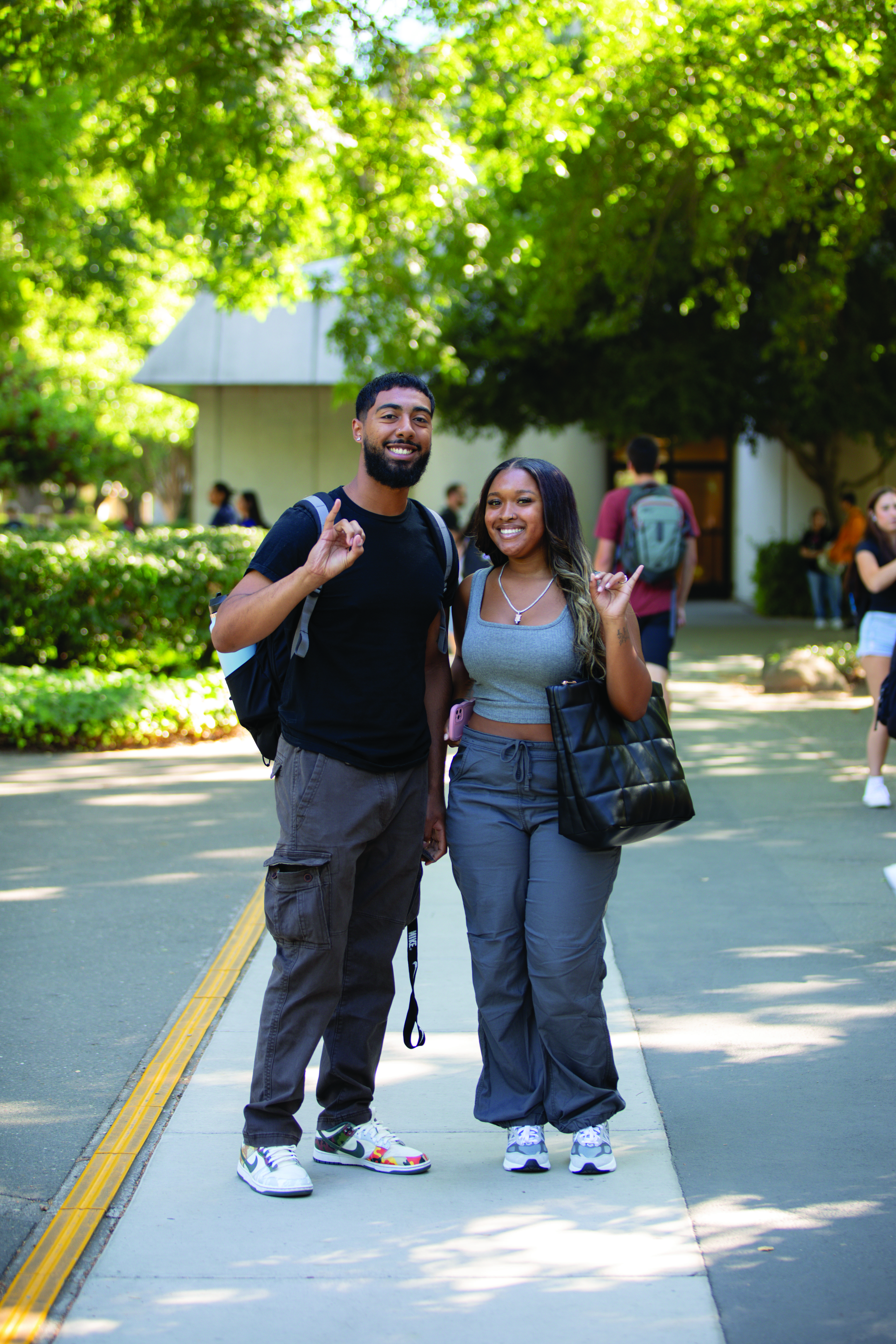 Image: male and female students smiling and doing stingers up